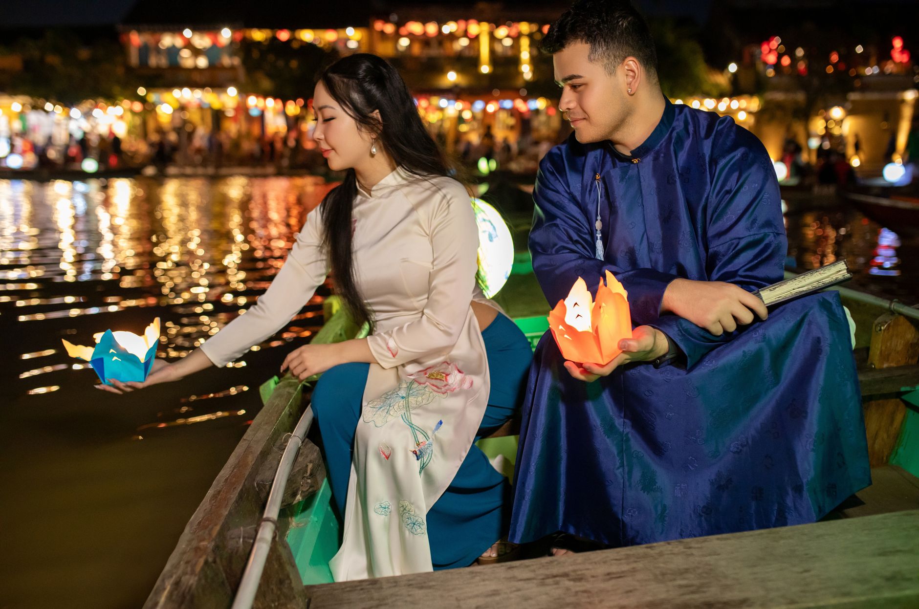 Couple releases lanterns in Hoi An, Vietnam, at night along the river.
