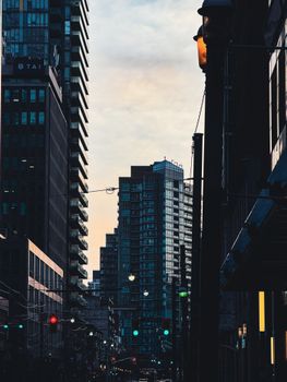 Evening view of city street with skyscrapers and streetlights at twilight.