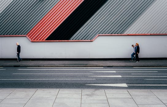 Urban scene with modern architectural wall and pedestrians on a city street.