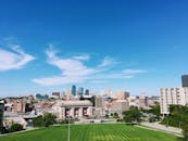 广角镜头下的堪萨斯城天际线，前景绿意盎然，映衬着蔚蓝天空