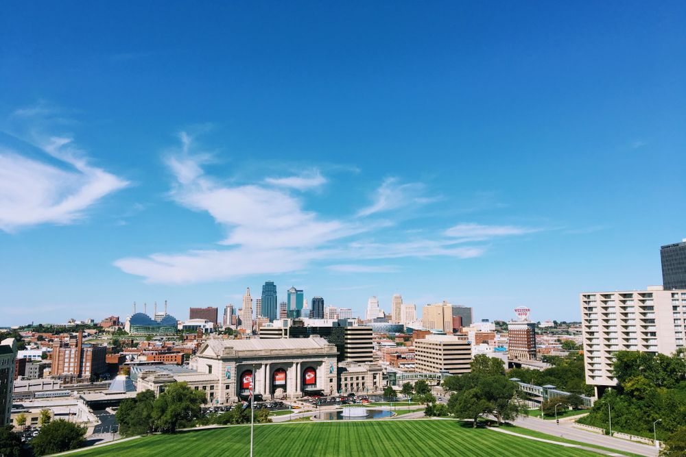 Wide-angle shot of Kansas City's skyline with clear blue skies and vibrant green foreground.
