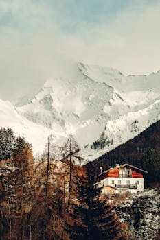 Charming alpine village nestled beneath snow-capped mountains in winter, showcasing serene beauty.