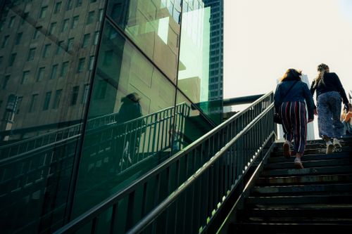 Free Two individuals ascend an urban staircase, reflecting city life in modern architecture. Stock Photo
