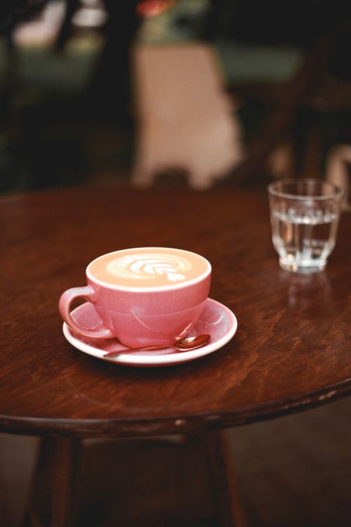 Free A warm latte in a pink cup on a cafe table, perfect for relaxing. Stock Photo