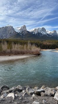 Scenic view of the Rocky Mountains with a clear flowing river under a blue sky.