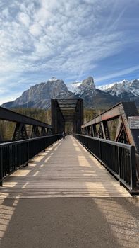 Majestic view of an iron bridge leading to snow-covered mountains in Banff.
