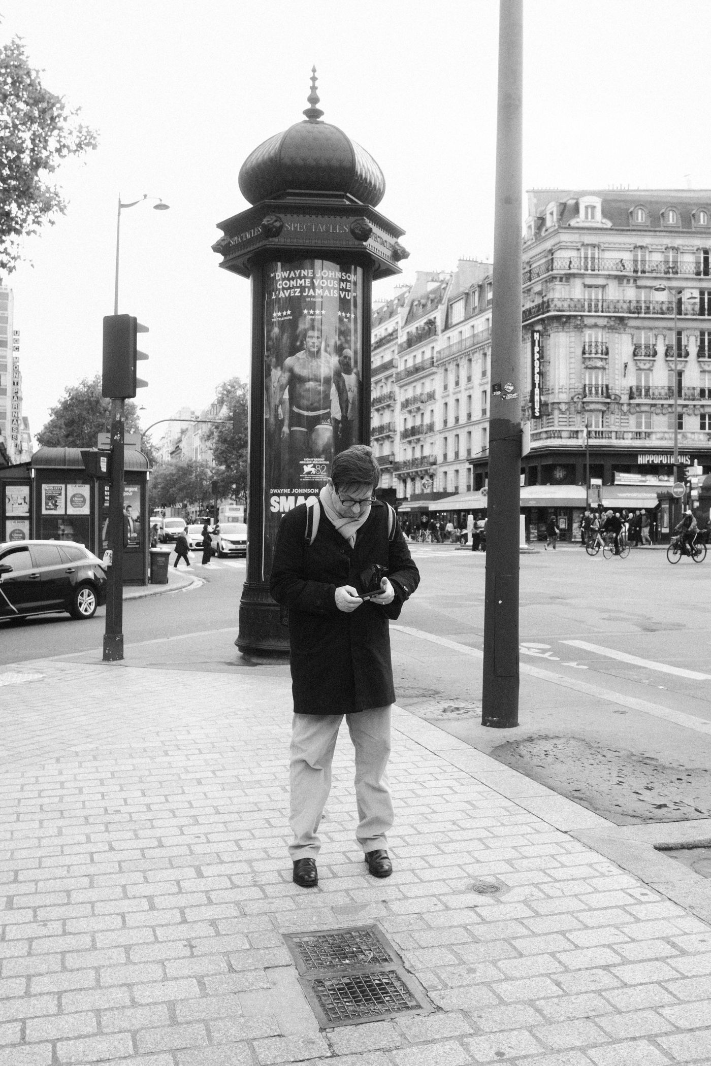 Homme consultant son téléphone dans une rue de Paris, en noir et blanc