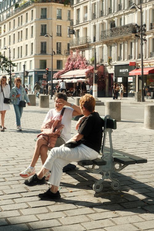 Free People enjoying a sunny afternoon at a Parisian square, showcasing classic architecture and vibrant city life. Stock Photo