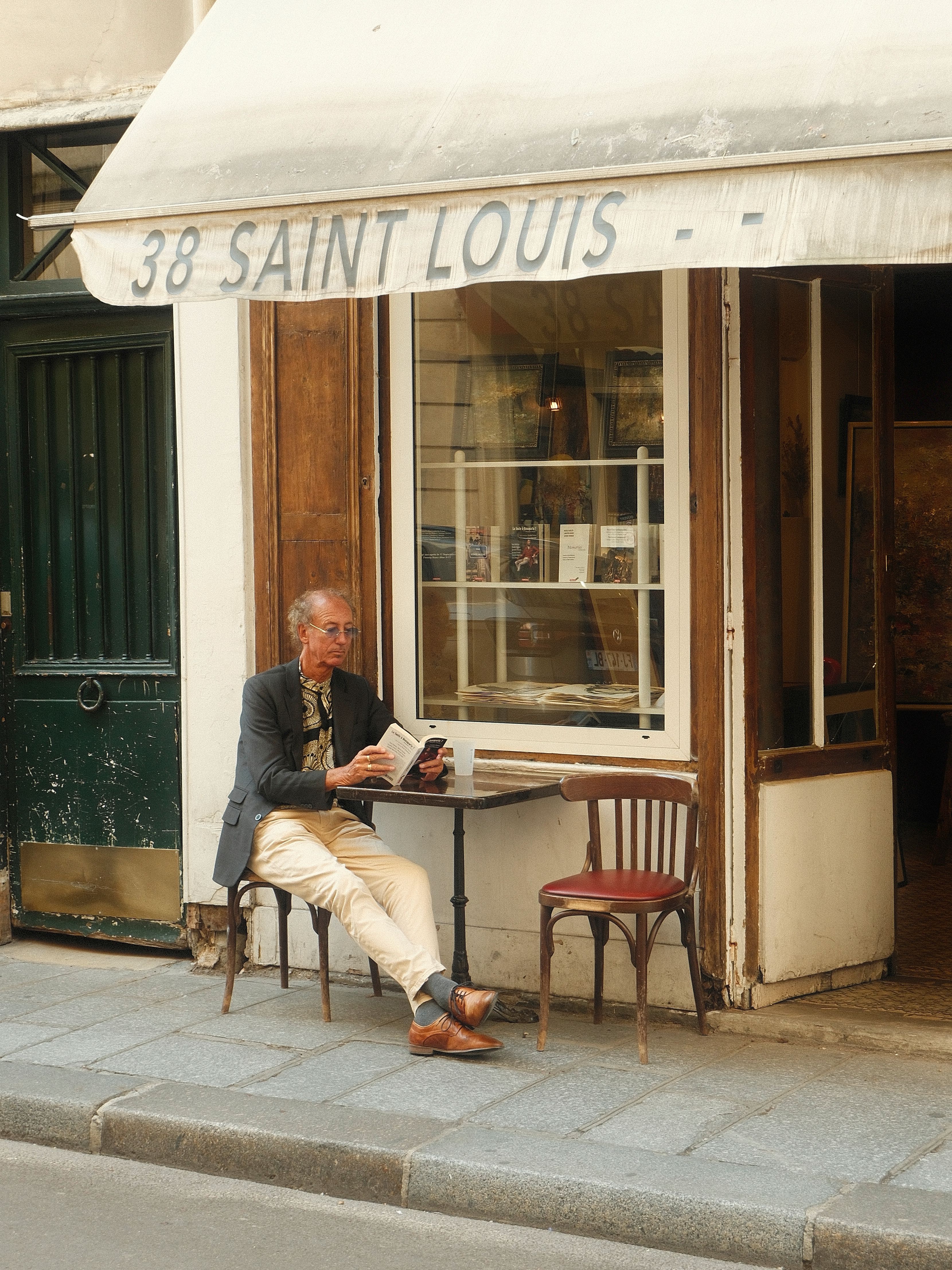 A man reading at a cafe table in Paris, evoking a relaxed atmosphere.