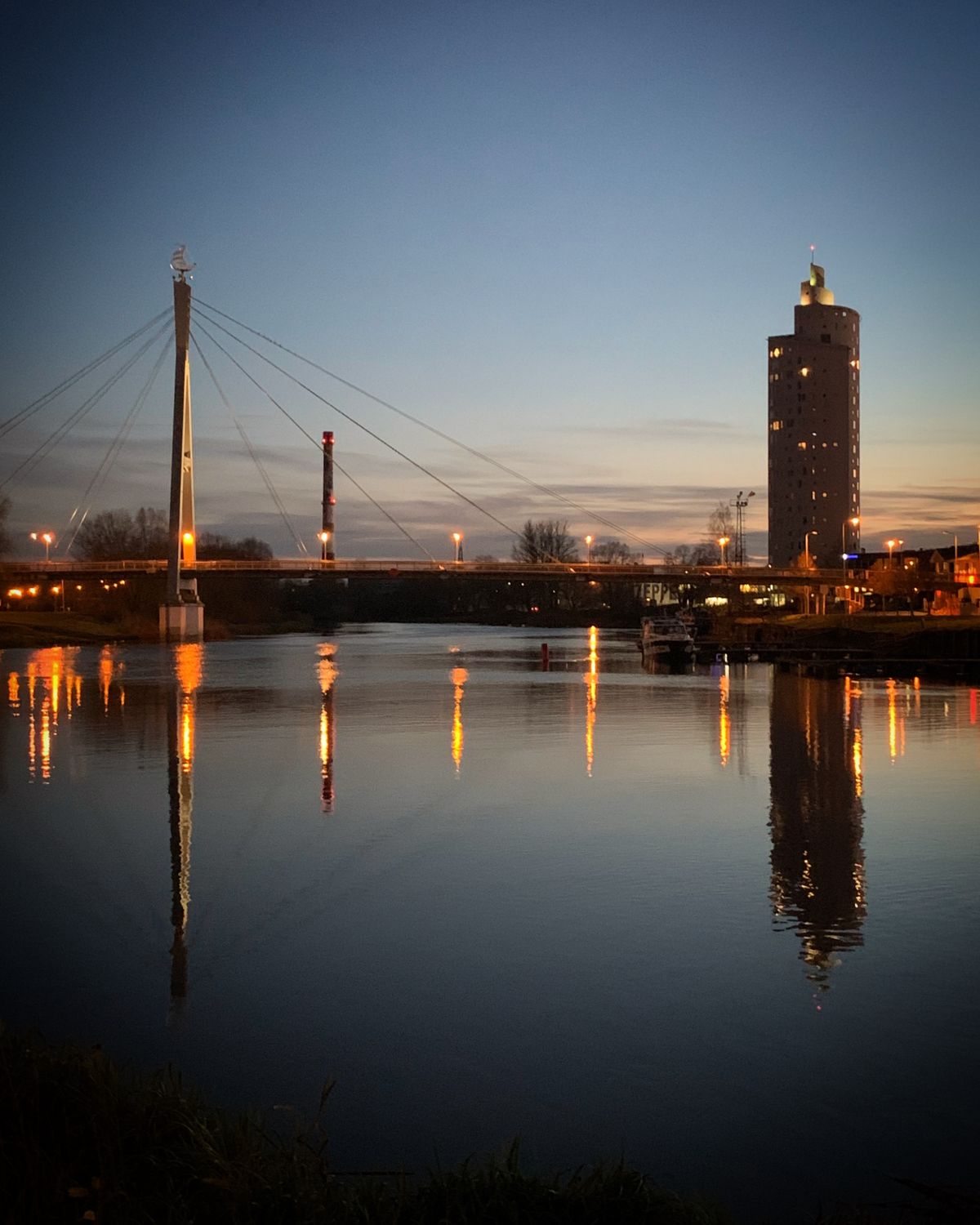 Tartu skyline and bridge reflected in the Emajogi river at twilight