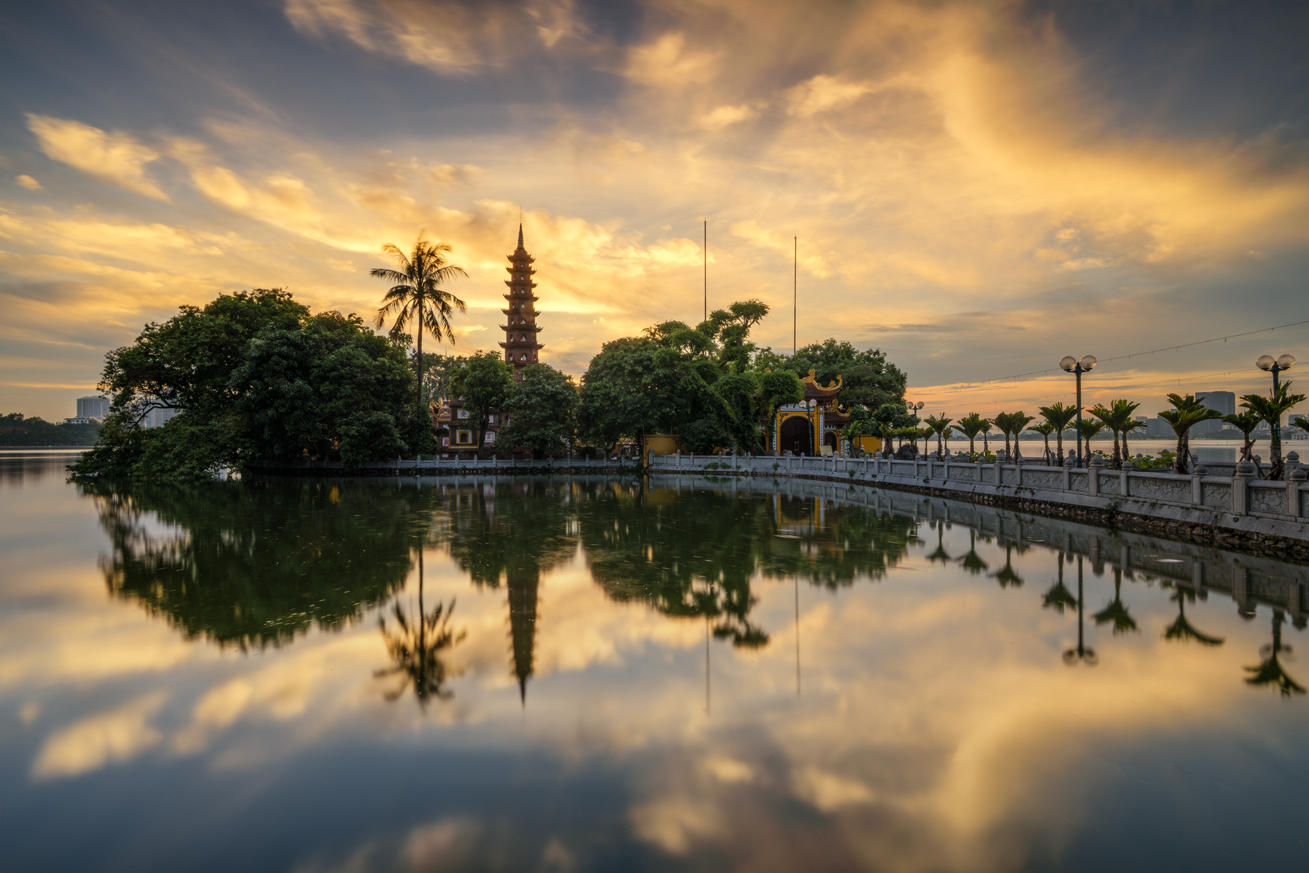 Tranquil sunset at Tran Quoc Pagoda with sky reflections on West Lake, Hanoi, Vietnam.
