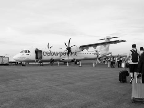 Cebu Pacific airplane at the airport with passengers boarding for departure.
