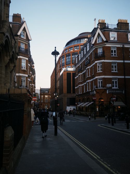 Free Quaint London street scene at twilight with classic architecture and pedestrians. Stock Photo