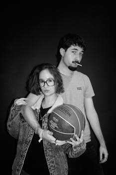 Black and white portrait of two young adults posing with a basketball, conveying a cool, laid-back vibe.