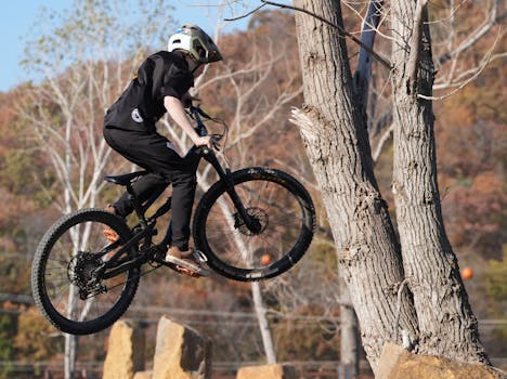 Ripresa dinamica di un ciclista in mountain bike che salta a mezz'aria in una suggestiva foresta autunnale.