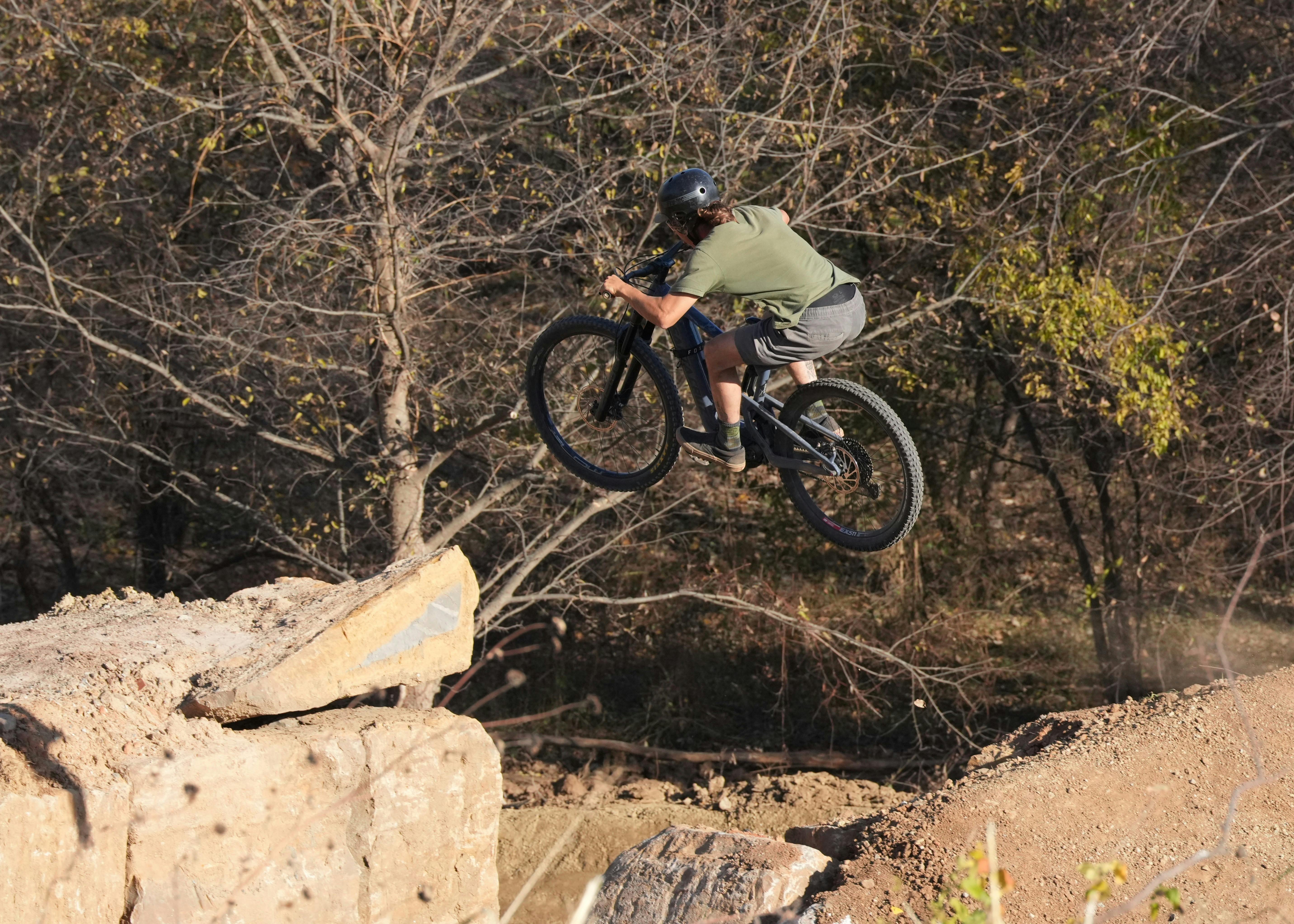 Exciting BMX rider performing a jump on an outdoor forest trail.