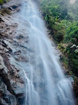 Dramatic waterfall cascading down rocky cliffs in scenic Araku Valley, India.