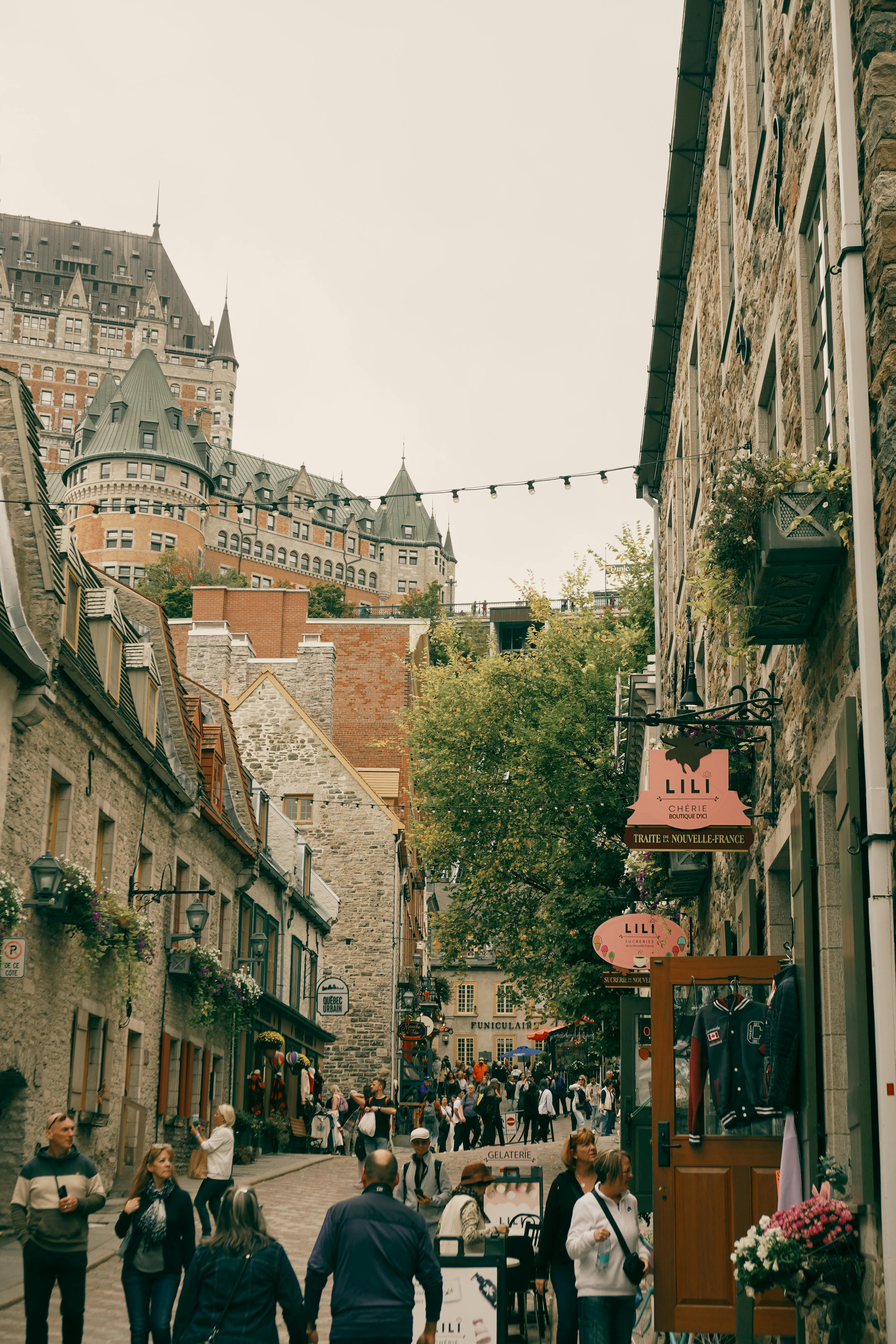 A picturesque street in Old Québec showcasing bustling life and iconic Château Frontenac in the background.