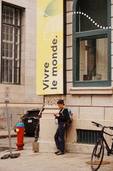 Street view of a person by a colorful 'Vivre le monde' sign in Québec city, Canada.