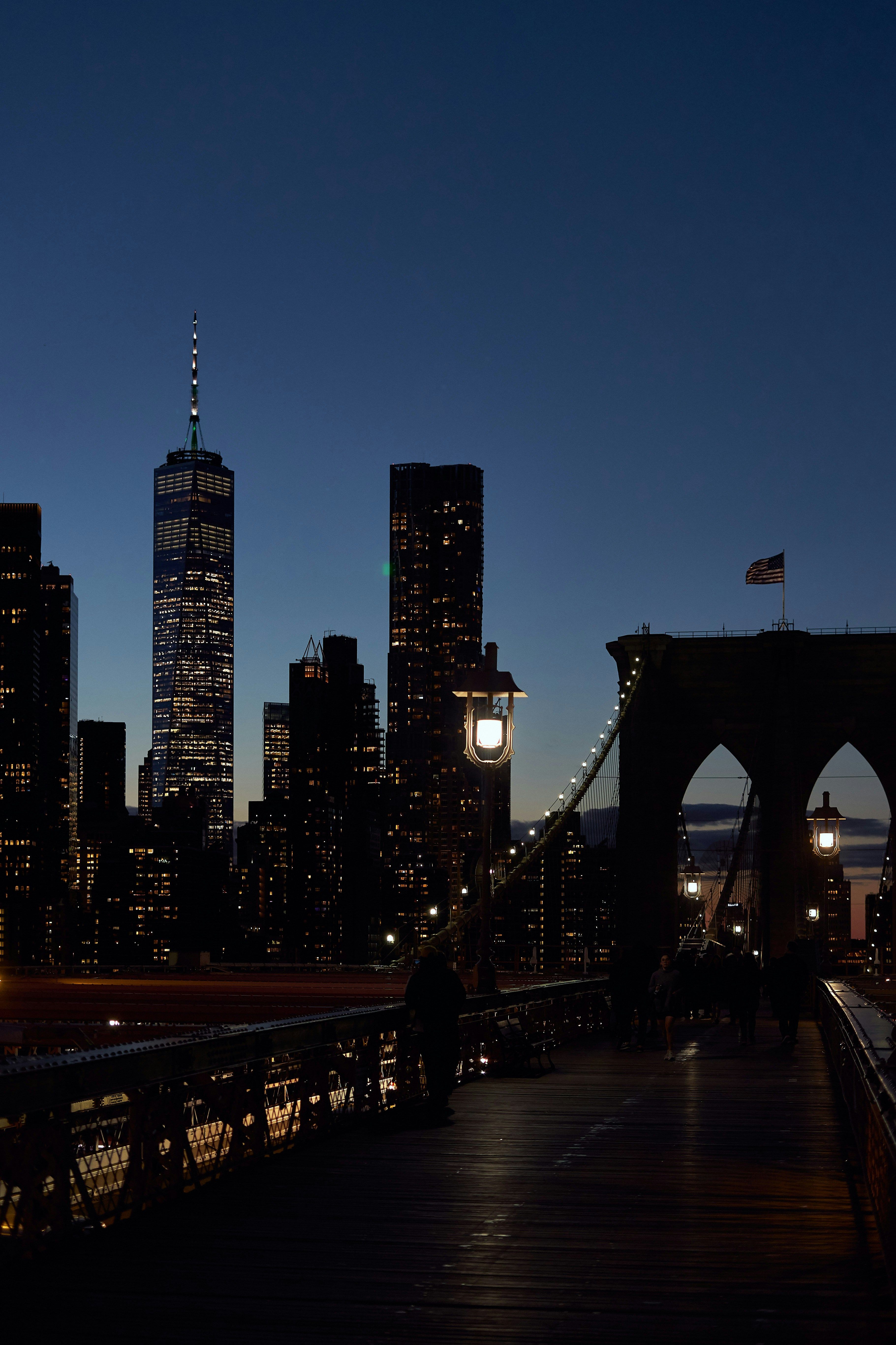 Fotomural Silhouette of the Brooklyn Bridge and New York City skyline at dusk with city lights glowing.