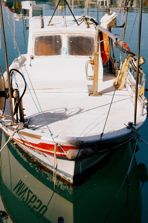 Free Fishing boat docked at a marina with clear blue water, under bright sunlight. Stock Photo