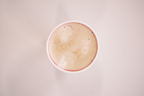 Free Minimalist top-down view of a frothy coffee cup on a light background. Stock Photo