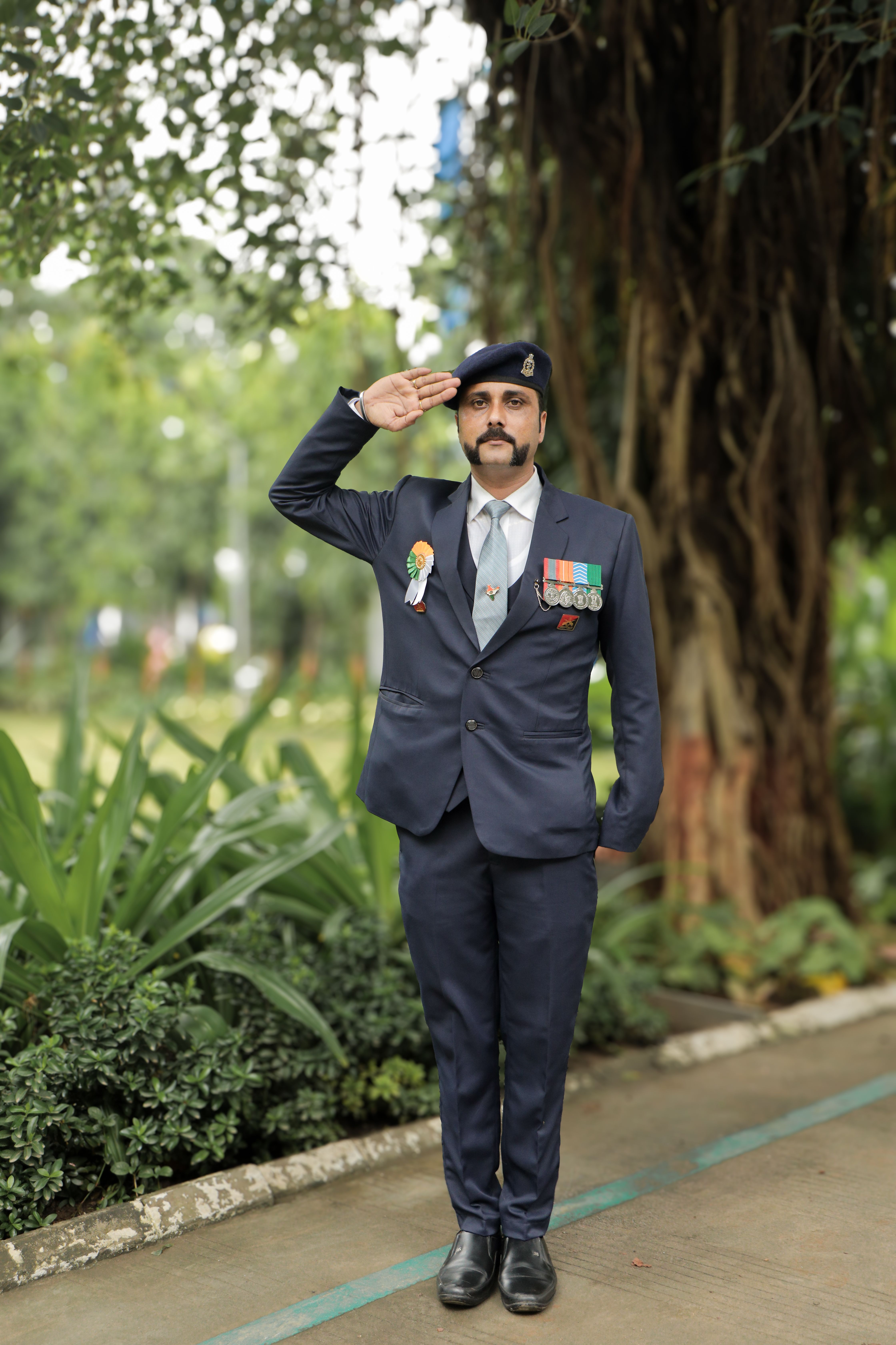 Proud Indian army officer in uniform saluting in a lush outdoor setting. The image depicts honor and service.