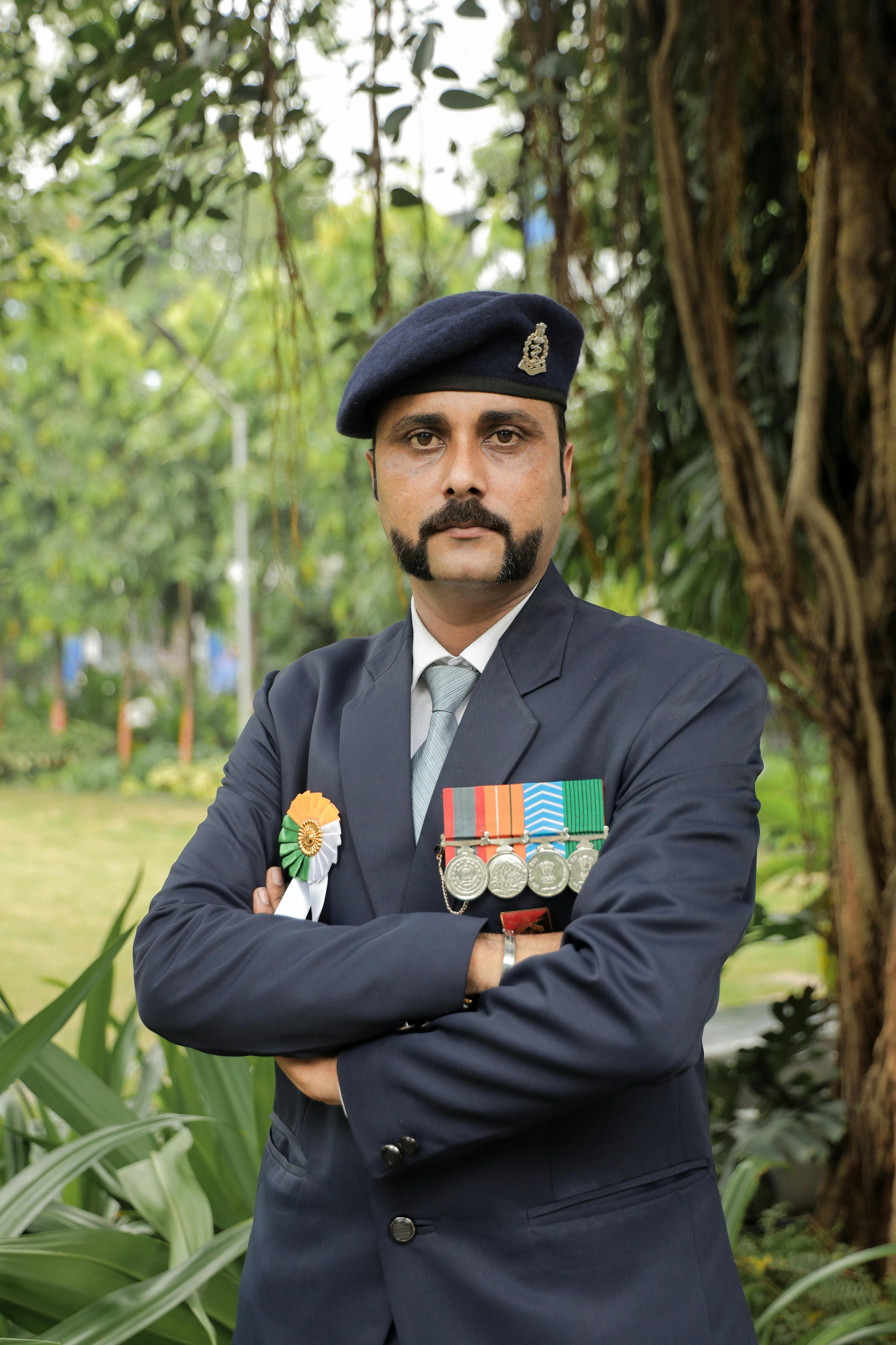 Portrait of a decorated Indian military officer standing in an outdoor setting, showcasing formal attire and medals.