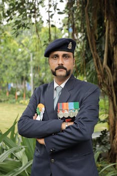 Portrait of a decorated Indian military officer standing in an outdoor setting, showcasing formal attire and medals.
