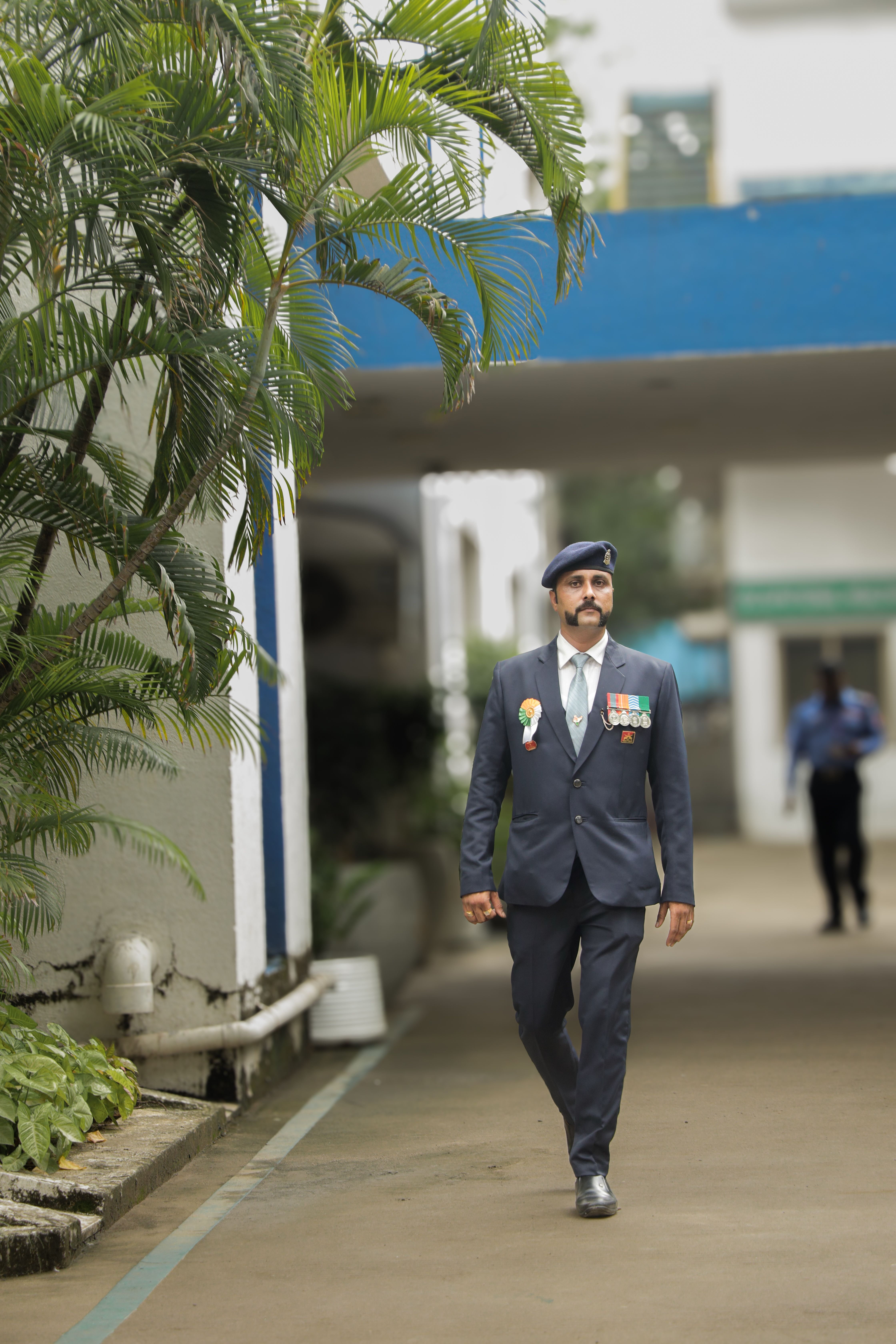 A distinguished Indian army officer in full uniform walking outdoors, showcasing medals and discipline.
