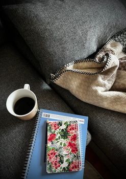 Inviting workspace with a coffee mug and floral notebook on a gray couch.