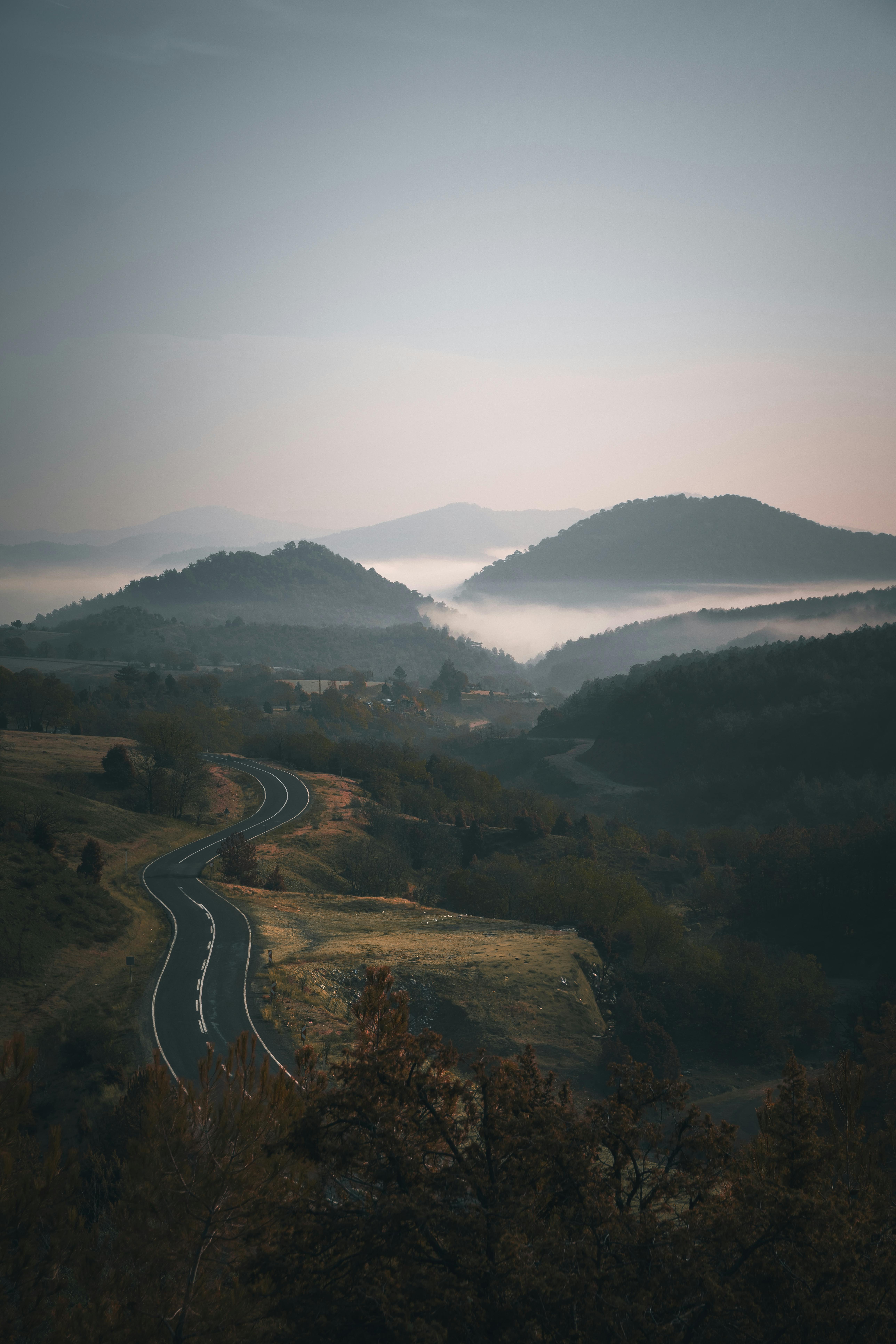 A winding road through misty mountains at dawn, creating a tranquil and scenic landscape.