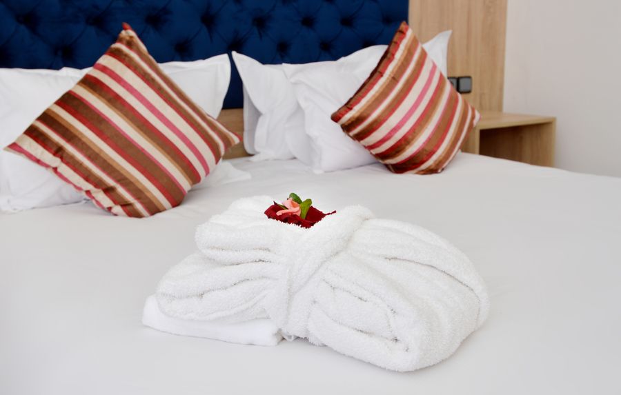 Plush pillows and neatly folded white towels on a freshly made bed
