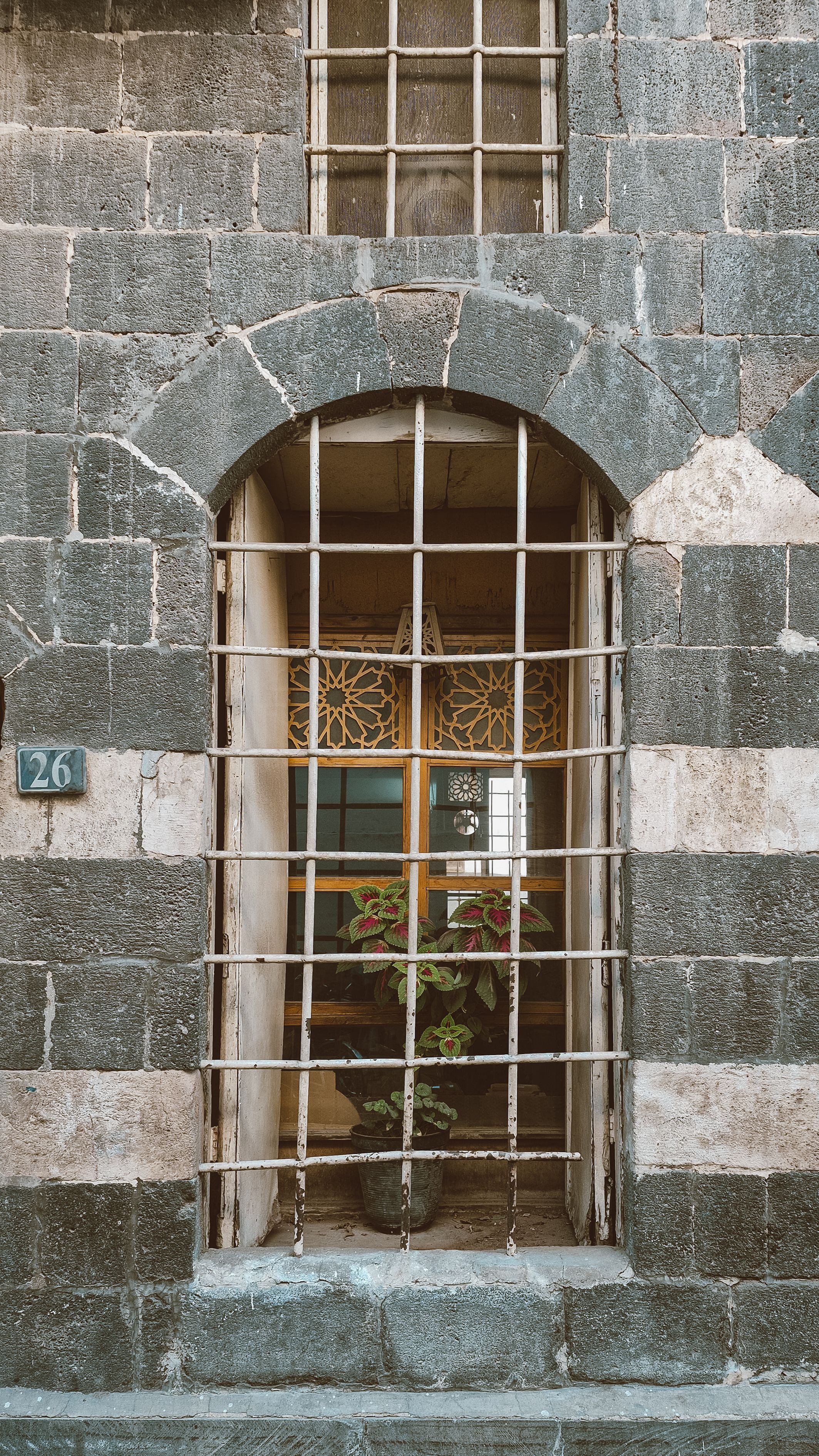 Gratis Et buet stenvindue med dekorative tremmer i det historiske Damaskus, Syrien, der fremviser traditionel arkitektur. Lagerfoto