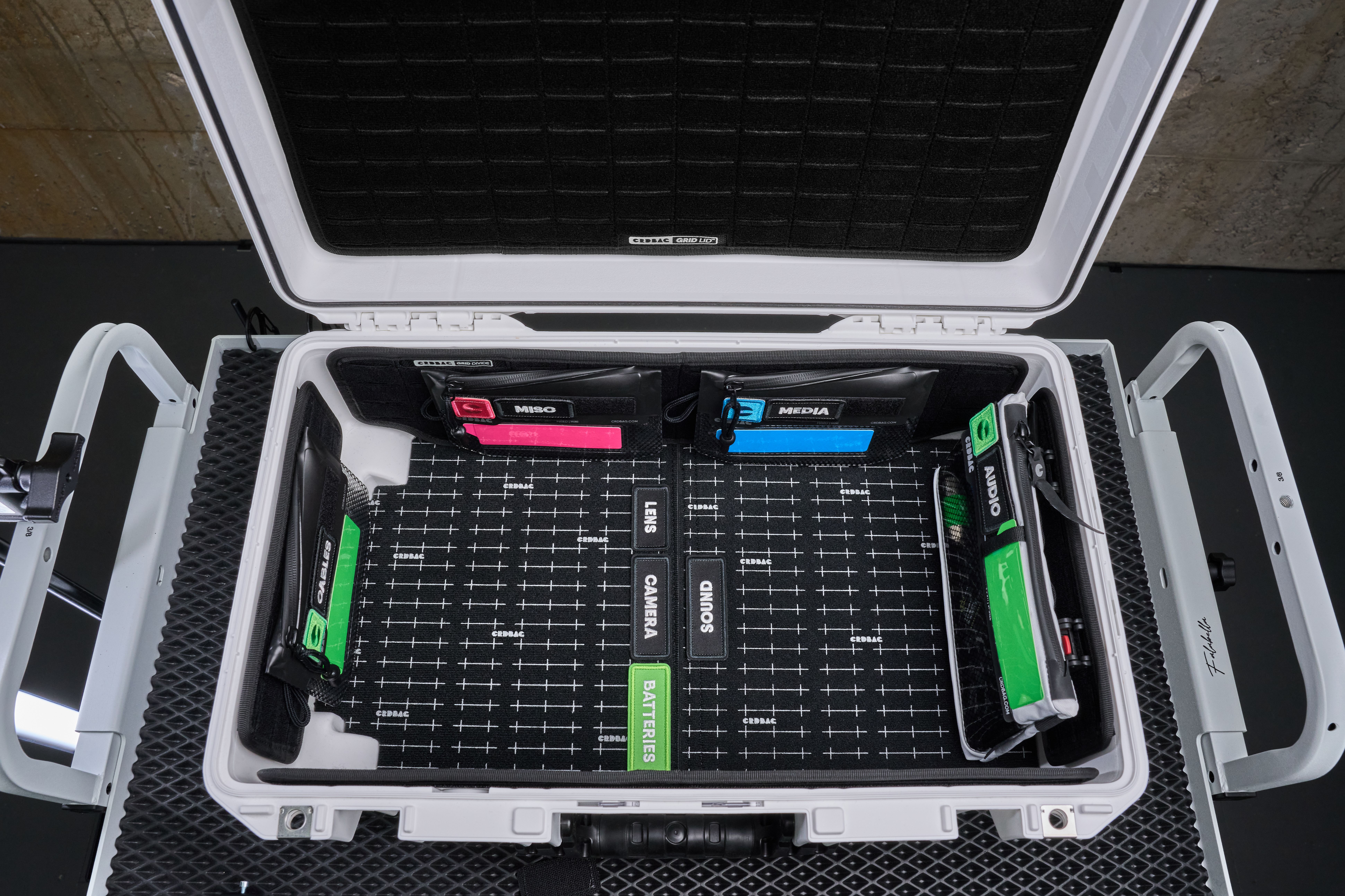 Top view of a neatly organized camera equipment hard case with labeled compartments.