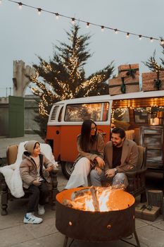 Family enjoying a warm campfire near a festive van with Christmas lights and decorations. - Fotografer Sidoarjo