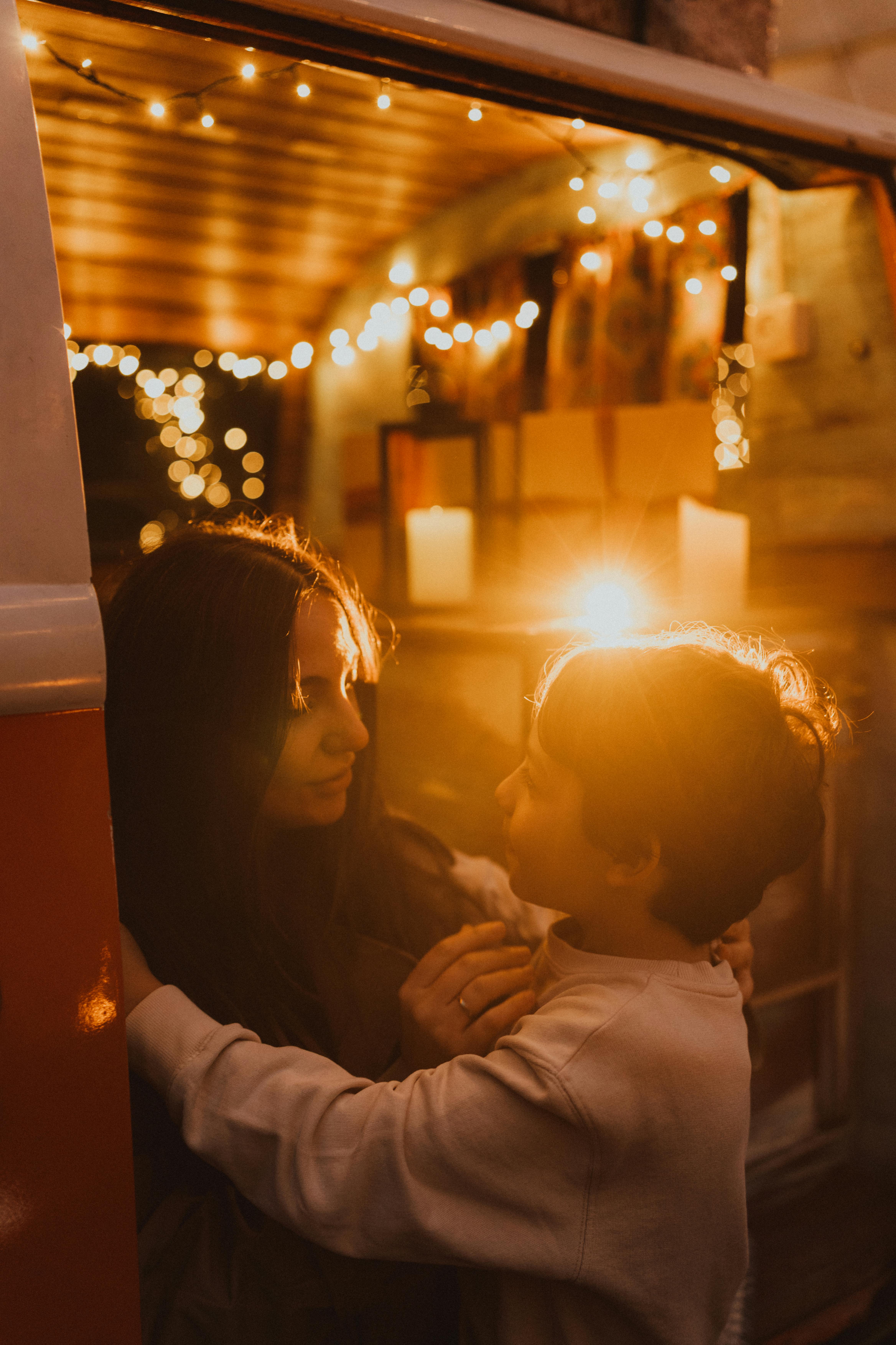 A warm, intimate moment between a woman and a child in a decorated van at sunset.