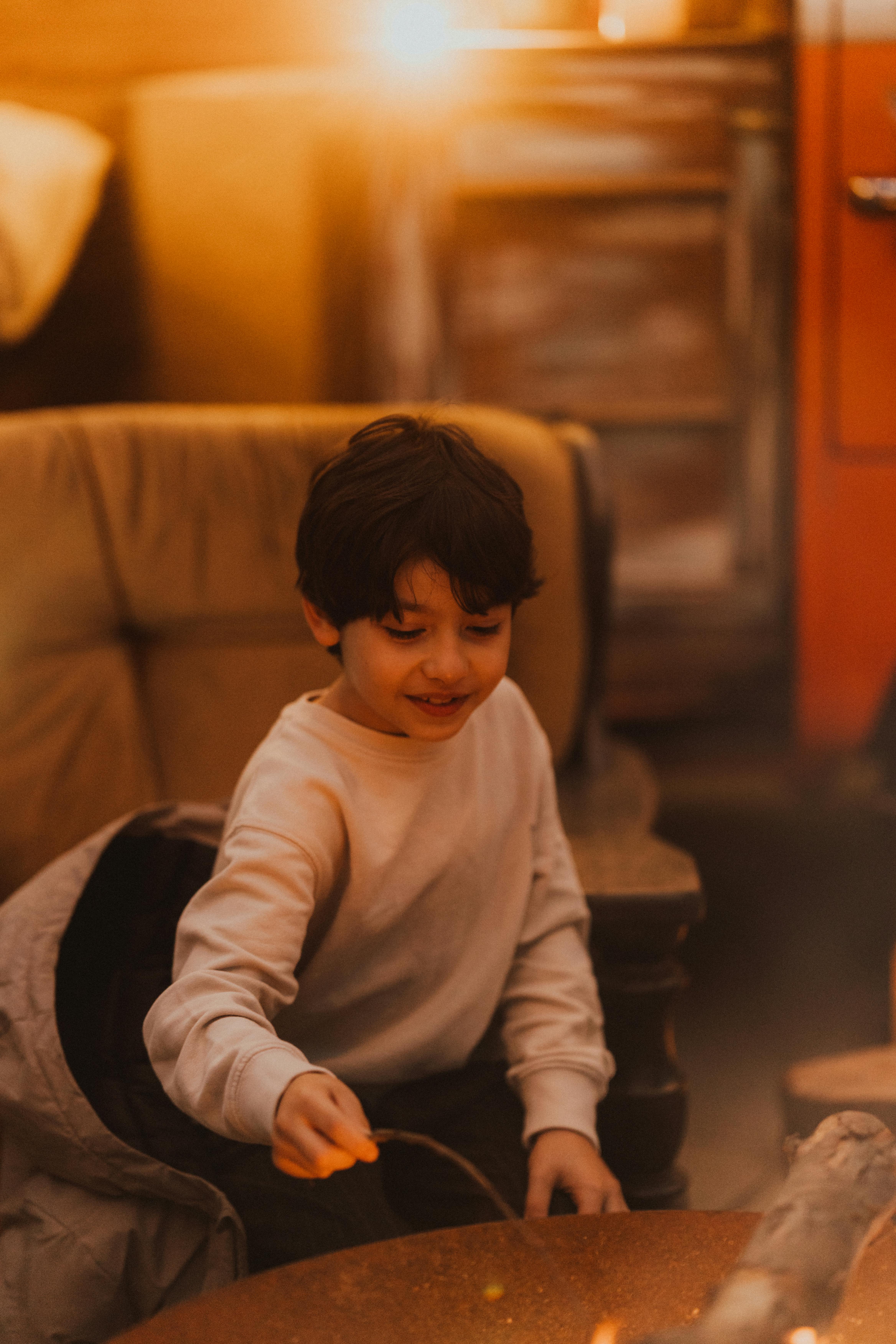 Безкоштовне Дитина насолоджується затишним критим багаттям у теплій сяючій атмосфері. стокове фото