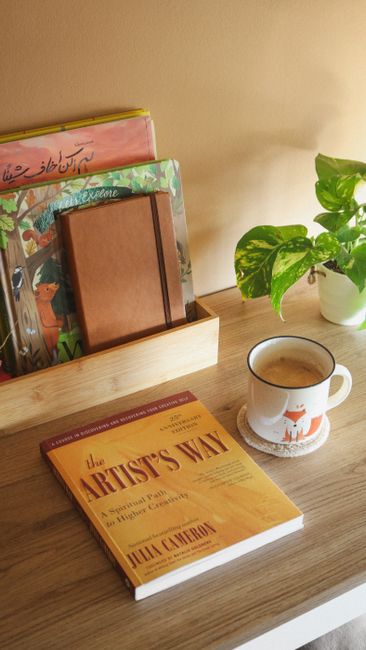 Warm and inviting reading nook featuring books, a coffee mug, and a plant on a wooden table.