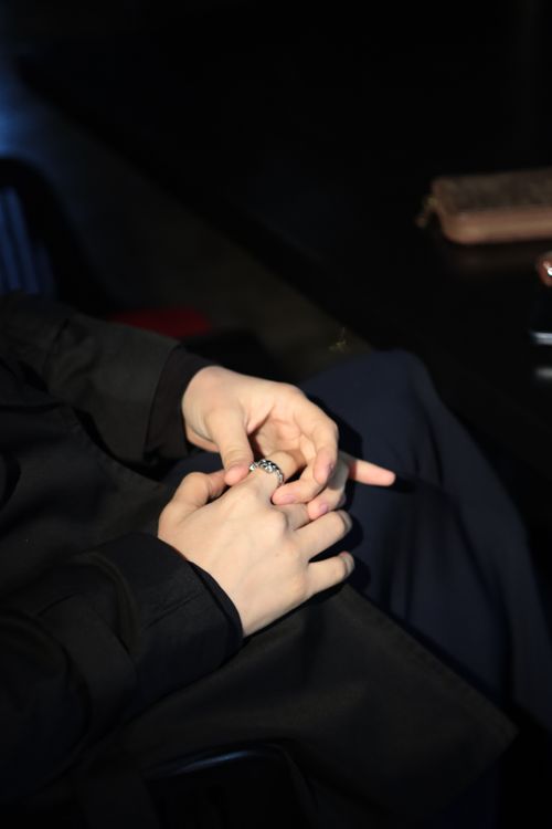 Free Hands adjusting a ring in a dimly lit environment, conveying elegance and focus. Stock Photo