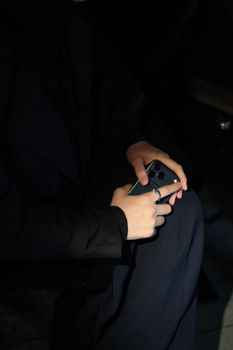 Close-up of hands holding a smartphone in a dimly lit interior space.