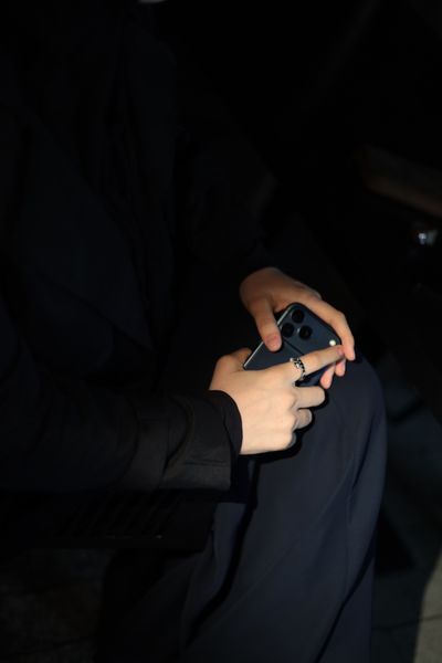 Close-up of hands holding a smartphone in a dim interior — photo by Lina Jan on Pexels