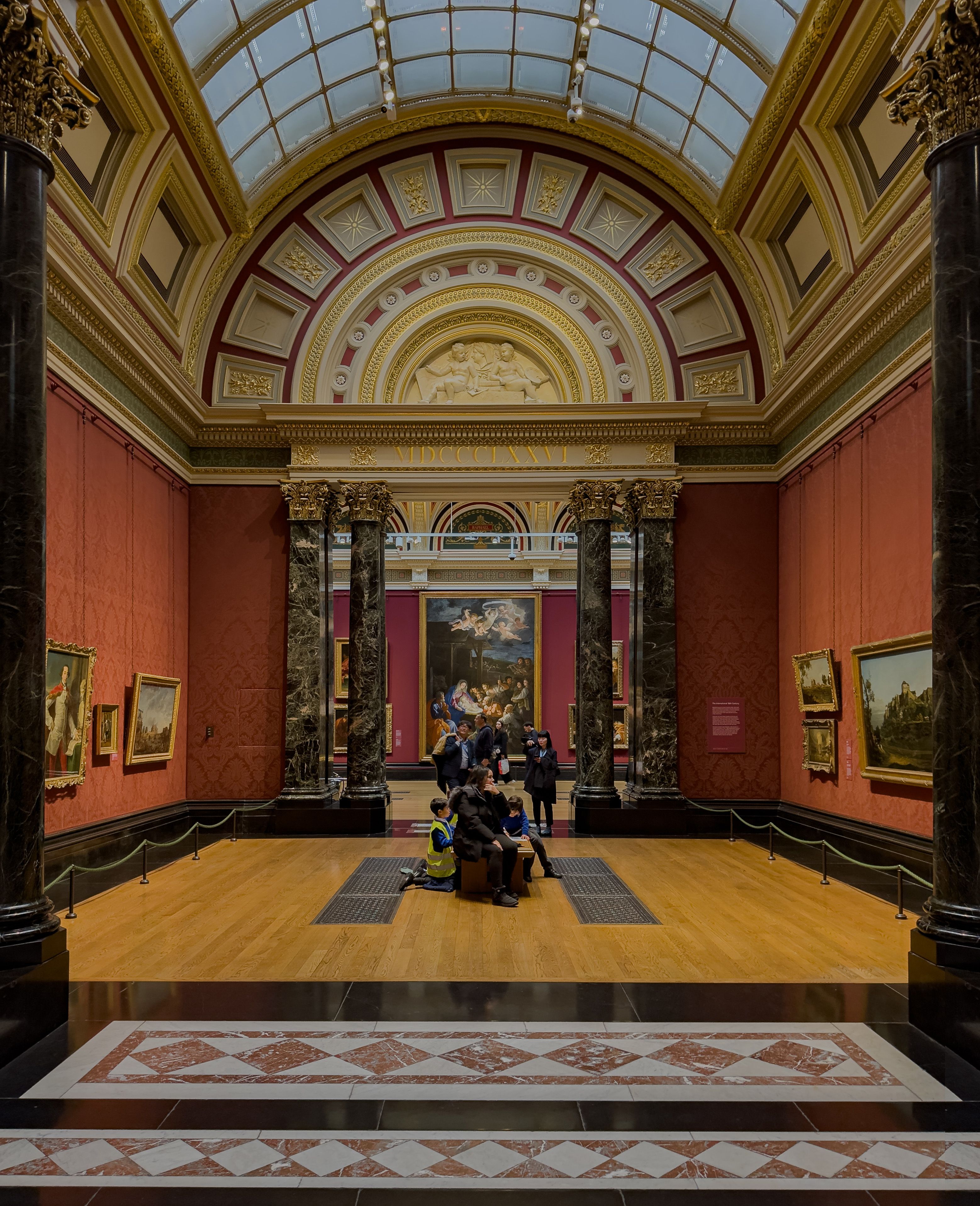 Visitors viewing paintings inside a grand room at the National Gallery on Trafalgar Square in London