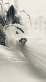 Sophisticated black and white image of a wedding bouquet adorned with an engagement ring on tulle.