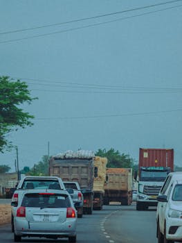 Traffic on a busy highway with multiple trucks and cars under a blue sky.