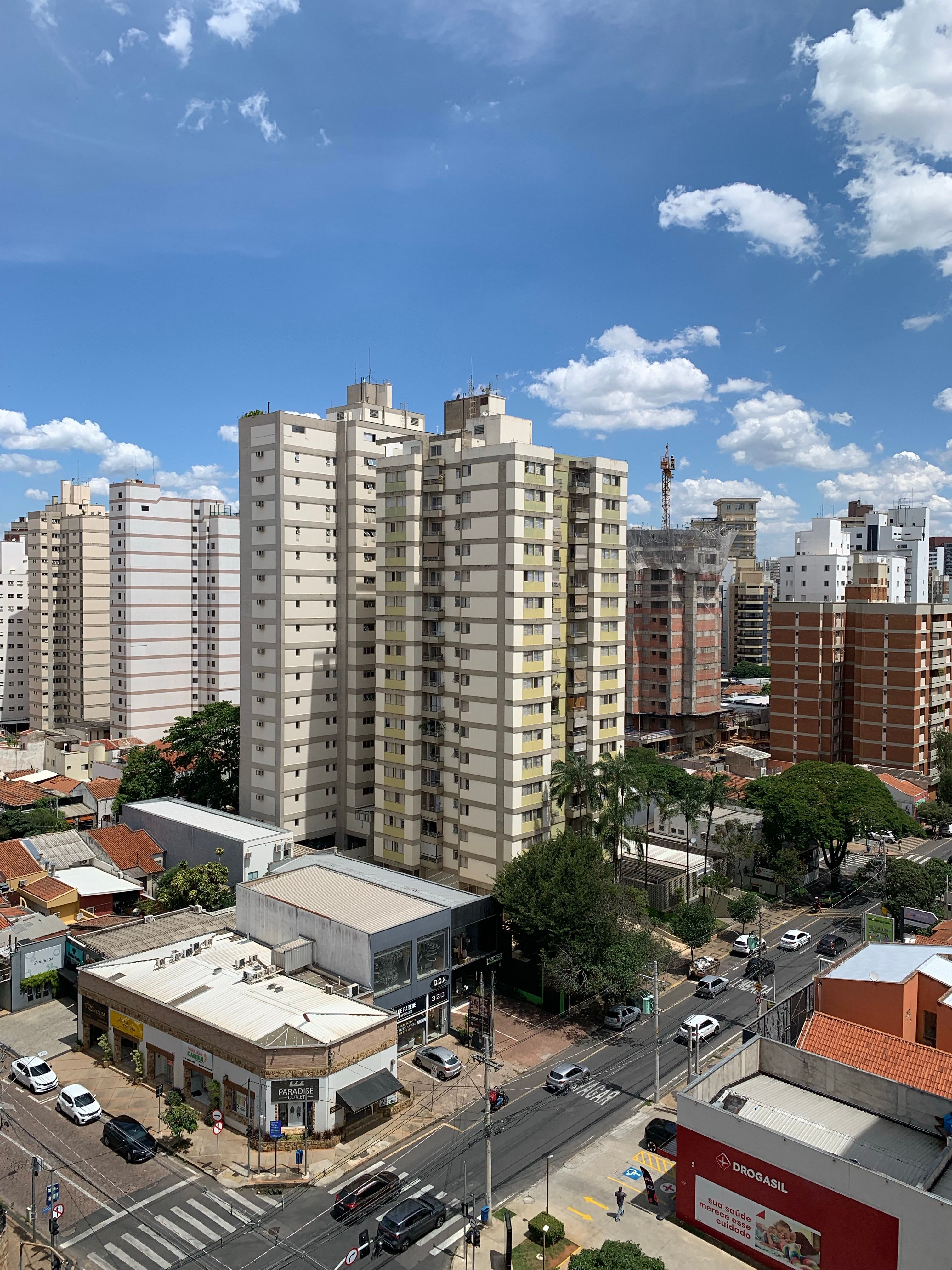 Cityscape showing tall apartment buildings under a bright blue sky, indicating a vibrant urban setting.