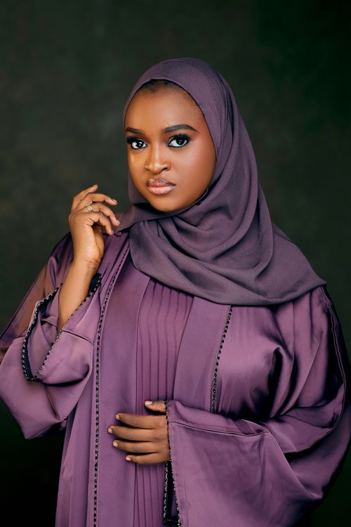Free Portrait of a woman wearing a purple hijab, expressing elegance and confidence. Stock Photo