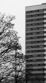 Black and white photo of a modern high-rise building with bare trees in Birmingham, UK.