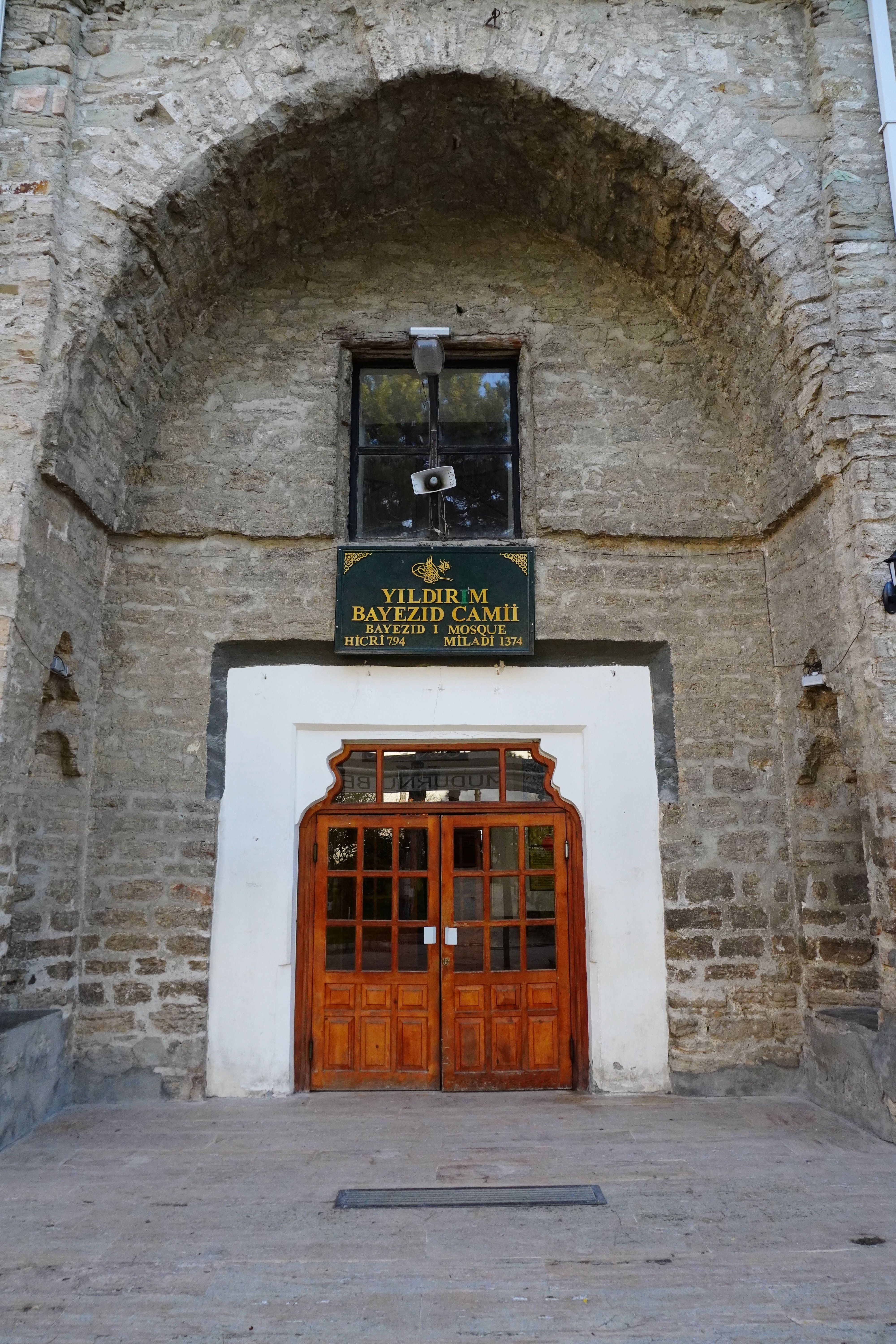Front view of the Yildirim Bayezid Camii with stone facade and wooden door in Izmit, Turkey.