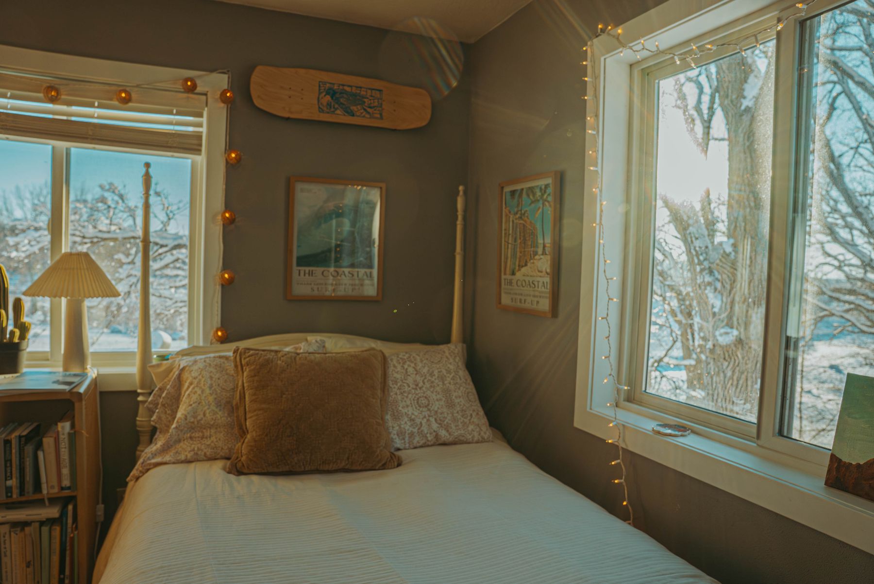 Cozy winter bedroom with warm light, soft bedding and a snowy view through the window